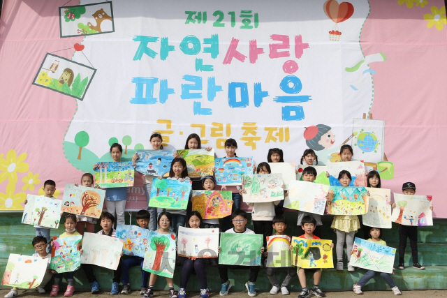 삼양그룹과 휴비스가 21일 휴비스 전주1공장 운동장에서 개최한 ‘제21회 자연사랑 파란마음 글·그림 축제’에 참여한 초등학생 어린이들이 자신이 그린 그림을 펼쳐 보이고 있다. 지난 1996년부터 시작된 글그림 축제는 삼양그룹과 휴비스 환경보전협회가 공동으로 개최하고 환경부가 후원하는 환경 축제로 해마다 1만여명이 참가해 인기를 끌고 있다. /사진제공=삼양그룹