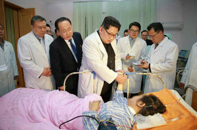 김정은(가운데) 북한 국무위원장이 관광 중 사고로 북한의 한 병실에 누워 있는 부상자들의 치료 상황을 살펴보고 있다고 노동신문이 24일 보도했다.   /연합뉴스