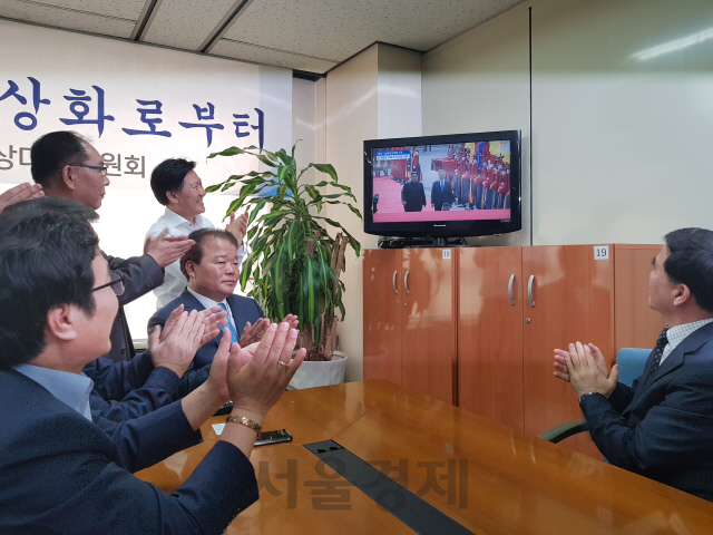 27일 서울 여의도 개성공단기업협회 사무실에서 TV를 시청하던 신한용(가운데) 개성공단기업협회 회장 등 개성공단 관계자들이 문재인 대통령과 김정은 북한 국무위원장이 공동 입장하는 장면이 나오자 박수를 치며 환호하고 있다./ 심우일기자