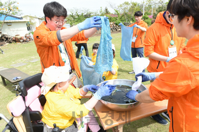 지난 26일부터 제주에서 열린 ‘S-OIL과 함께하는 햇살나눔 캠프’에 참여한 자원봉사자와 희귀 난치 질환 어린이가 천연염색 체험을 하고 있다. S-OIL은 2006년부터 해마다 행사를 진행하고 있으며 올해까지 800여명의 어린이와 가족들이 참여했다. /사진제공=S-OIL