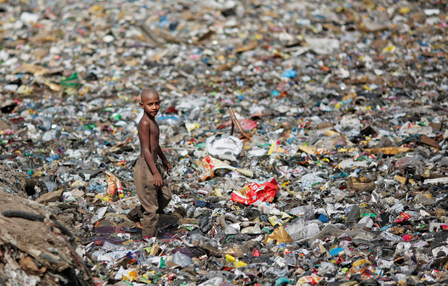 인도의 한 소년이 지난 4월23일(현지시간) 뉴델리 쓰레기 매립장 위를 걷고 있다.    /로이터연합뉴스
