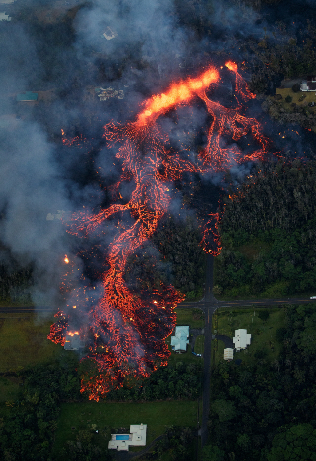 epa06716039 Volcanic activity continues on Kilauea‘s east rift zone, as a robust fissure eruption in Leilani Estates sends a massive flow into the subdivision, consuming all in its path, near Pahoa, Hawaii, USA, 06 May 2018. A local state of emergency has been declared after Mount Kilauea erupted near residential areas, forcing mandatory evacuation of about 1,700 citizens from their nearby homes. The crater’s floor collapsed on 01 May and is since then continuing to erode its walls and generating huge explosions of ashes. Several earthquakes have been recorded in the area where the volcanic eruptions continue, including a 6.9 magnitue earthquake which struck the area on 04 May.  EPA/BRUCE OMORI / PARADISE HELICOPTERS      <저작권자(c) 연합뉴스, 무단 전재-재배포 금지>