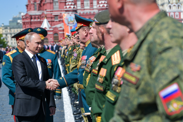 블라디미르 푸틴(왼쪽) 러시아 대통령이 9일 모스크바 붉은광장에서 열린 2차 세계대전 승전 73주년 군사퍼레이드에 참석해 한 장교와 악수하고 있다.    /모스크바=타스연합뉴스