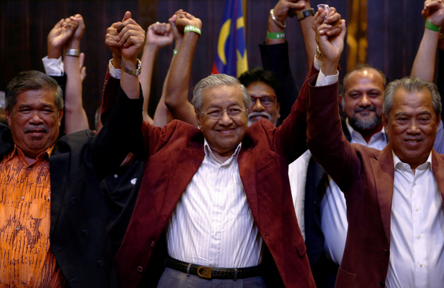 마하티르 모하맛 전 말레이시아 총리가 10일(현지시간) 프탈링자야에서 열린 기자회견에서 전날 치러진 총선 승리를 확인하고 지지자들과 함께 두 손을 들어 보이며 환호하고 있다. /프탈링자야=로이터연합뉴스