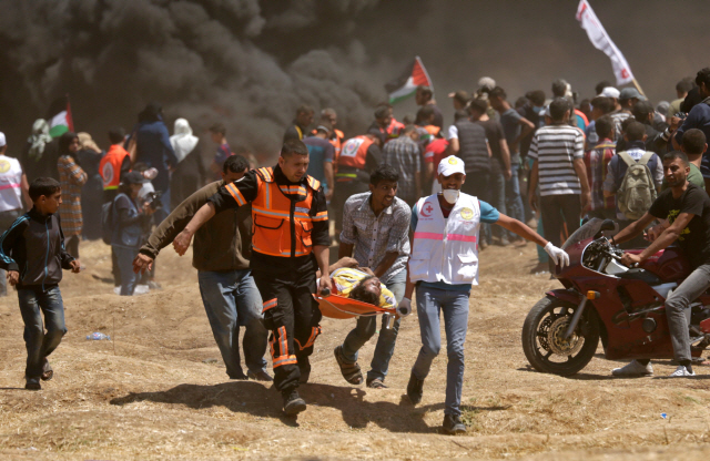 팔레스타인 시위대가 14일(현지시간) 가자지구와 이스라엘 접경지대에서 대규모 시위를 벌이다 유혈사태가 발생하면서 사상자들이 들것에 실려 옮겨지고 있다 . /가자지구=AFP연합뉴스