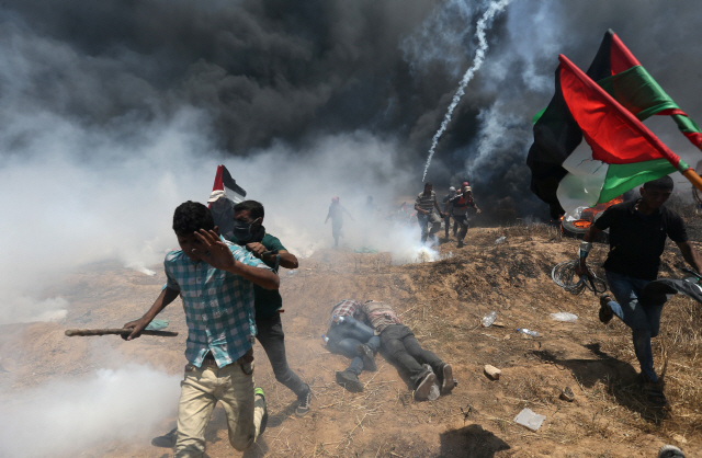 14일(현지시간) 이스라엘 미국대사관 예루살렘 이전을 반대하는 팔레스타인 시위대들이 팔레스타인 가자지구-이스라엘 국경에서 이스라엘군의 진압에 대피하고 있다. / (로이터)연합뉴스