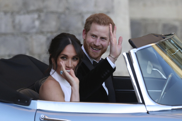 지난 19일(현지시간) 런던 인근 윈저 성의 세인트 조지 예배당에서 결혼식을 마친 해리 왕자(33)와 할리우드 여배우 출신 메건 마클(36)이 윈저 성을 나서며 손을 흔들고 있다. /런던=AP연합뉴스