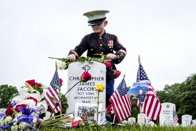 epa06769800 On Memorial Day, Christian Jacobs, 7, of Hertford, NC, tends the gravesite of his father, Marine Sgt. Christopher Jacobs, in Section 60 at Arlington National Cemetery in Arlington, Virginia, USA, on 28 May 2018. Section 60, is the burial ground in the cemetery where military personnel killed in the Global War on Terror since 2001 are interred.  EPA/PETE MAROVICH      <저작권자(c) 연합뉴스, 무단 전재-재배포 금지>