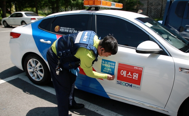 에스원 출동요원이 출동차량에 6·25전사자 유해발굴사업 안내문을 부착하고 있다. /사진제공=에스원