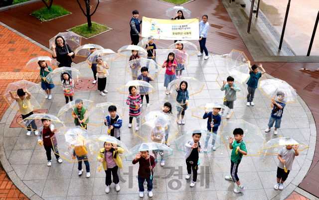 경기도 고양시 아람초등학교 학생들이 현대모비스가 제공한 투명우산을 들고 손을 흔들고 있다. /사진제공=현대모비스