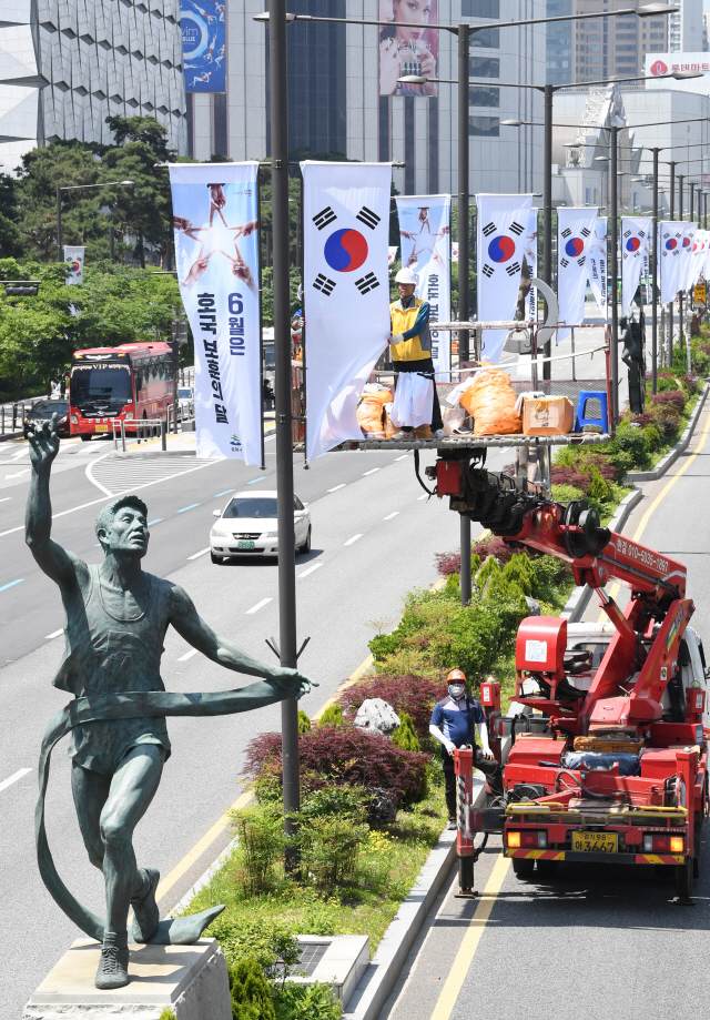 6월 호국보훈의 달을 하루 앞둔 31일 서울 송파구 올림픽로에서 구청 관계자들이 호국보훈기와 태극기를 게양하고 있다./권욱기자