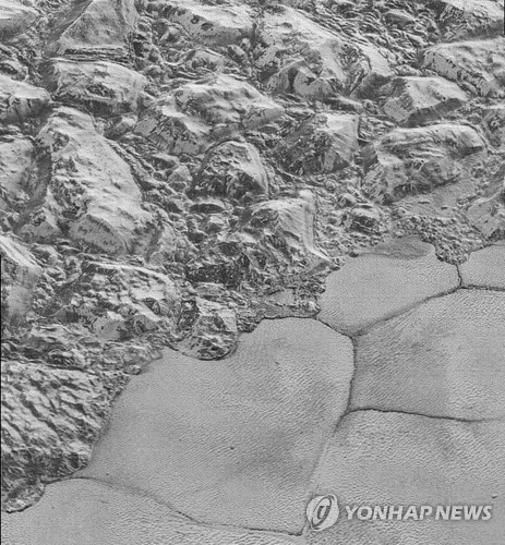 명왕성의 산맥과 평원 사이에 얼음알갱이로 만들어진 언덕이 사진 밑쪽에 보인다./연합뉴스
