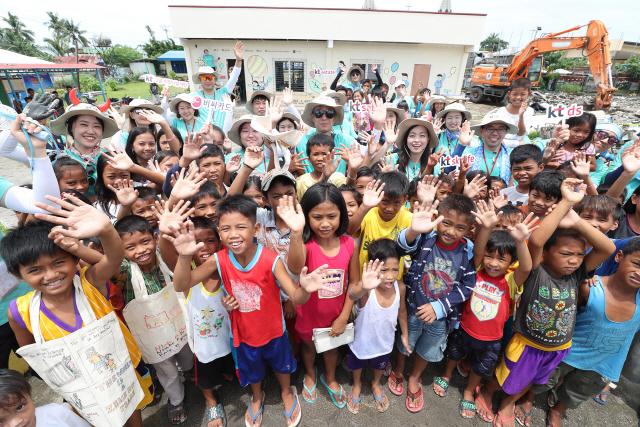 KT 그룹 임직원들과 필리핀 타클로반 레이테시 둘락 지역 산호세 센트럴 초등학교 학생들이 손을 흔들고 있다./사진제공=KT