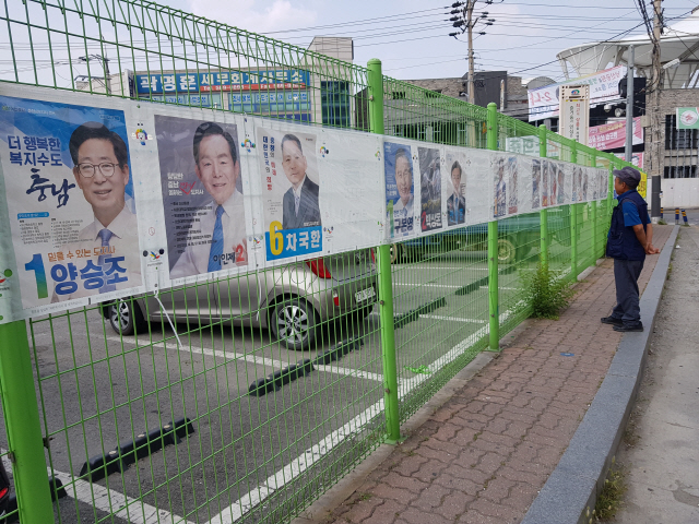 5일 충남 천안 중앙시장 인근에서 한 시민이 충남지사 후보 등 선거 포스터를 유심히 살펴보고 있다.     /천안=박우인기자