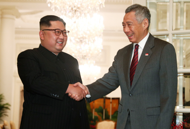 김정은(왼쪽) 북한 국무위원장이 10일(현지시간) 리셴룽 싱가포르 총리와 악수하고 있다. /싱가포르=로이터연합뉴스