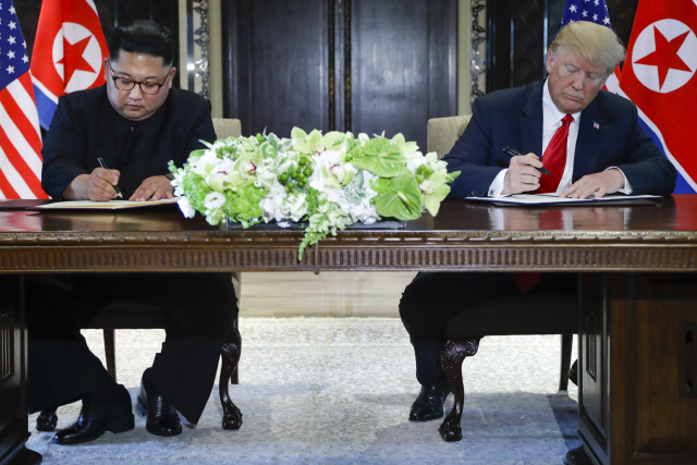 김정은(왼쪽) 북한 국무위원장과 도널드 트럼프(오른쪽) 미국 대통령이 12일(현지시간) 싱가포르 센토사섬 카펠라호텔에서 북미 정상회담을 한 뒤 공동합의문에 서명하고 있다. /싱가포르=로이터연합뉴스