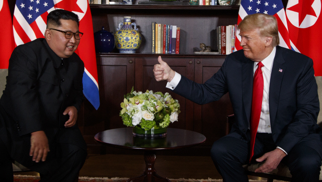 도널드 트럼프(오른쪽) 미국 대통령이 12일(현지시간) 싱가포르 카펠라호텔에서 김정은 북한 국무위원장과의 단독회담을 시작하며 엄지를 치켜들어 올리자 김 위원장이 밝게 웃고 있다.  /싱가포르=AP연합뉴스