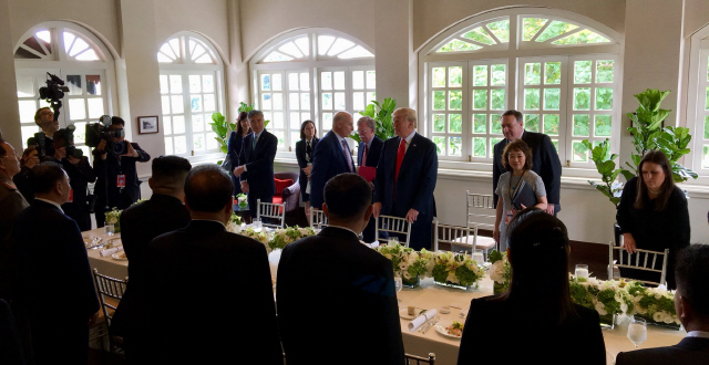 도널드 트럼프(뒷줄 가운데) 미국 대통령과 김정은(앞줄 왼쪽 세번째) 북한 국무위원장이 각각 실무 협상팀과 함께 싱가포르 카펠라호텔 오찬장에서 착석 준비를 하고 있다.    /댄 스커비노 주니어 백악관 소셜미디어국장 트위터 캡처