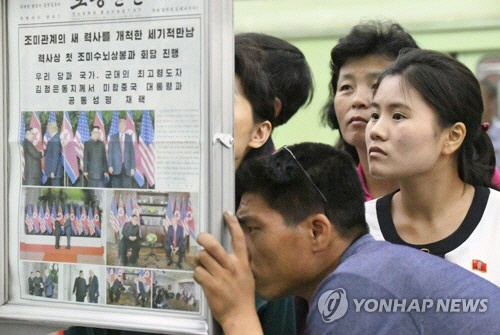 싱가포르에서 역사적인 북미 정상회담이 열린지 하루가 지난 13일 북한 평양의 한 지하철역 신문 게시 코너에 뉴스를 보려는 시민들이 몰려들었다./연합뉴스