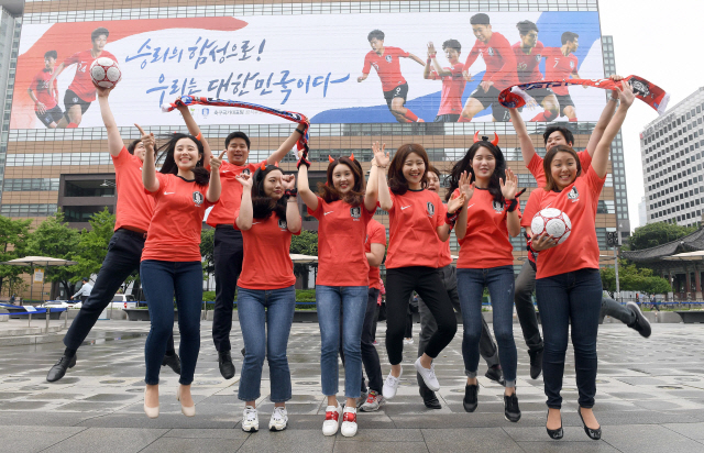 교보생명 직원들이 14일 서울 광화문광장에서 광화문 교보생명빌딩 외벽에 설치된 대형 걸개그림 앞에서 2018 러시아 월드컵 태극전사들의 성공을 기원하는 세리머니를 하고 있다./이호재기자.