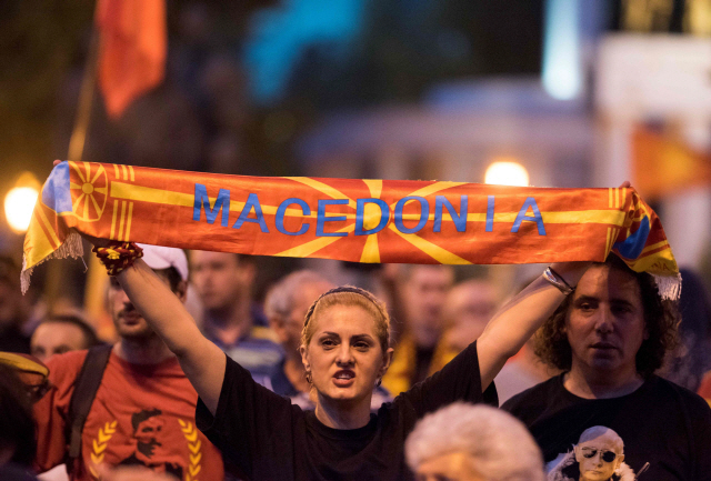 A demonstrator holds a banner reading ‘Macedonia’ in front of the parliament building in Skopje on June 13, 2018 during a protest against the new name of the country.  Greeks and Macedonians expressed scepticism on June 13 over a proposed compromise deal to end a nearly three-decade name row between their countries which has blocked Skopje‘s bid to join the EU and NATO. The leaders of the neighbouring countries hailed a “historic” agreement on June 12 to rename the tiny Balkan nation the Republic of North Macedonia after months of intensive talks. / AFP PHOTO / Robert ATANASOVSKI      <저작권자(c) 연합뉴스, 무단 전재-재배포 금지>