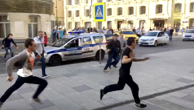 러시아 모스크바 중심부에서 일어난 택시 인도 돌진 사고 후 사고 택시 운전자(오른쪽)가 달아나고 있고 행인들이 그를 쫒고 있다./AP연합뉴스