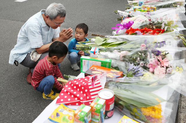 Residents pray at an altar for a nine-year-old student who was killed in an earthquake near an elementary school in Takatsuki city, Osaka prefecture on June 19, 2018.  The death toll in a powerful earthquake that rocked Japan‘s Osaka on on June 18 has risen to four, with over 380 injured, officials said on June 19, urging vigilance against landslides ahead of heavy rains. / AFP PHOTO / JIJI PRESS / JIJI PRESS / Japan OUT      <저작권자(c) 연합뉴스, 무단 전재-재배포 금지>