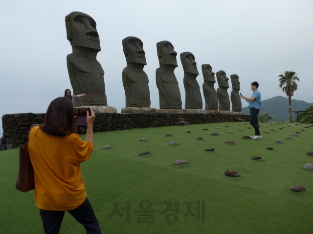 여행객들이 ‘선멧세 니치난’의 모아이 석상 앞에서 사진을 찍고 있다.