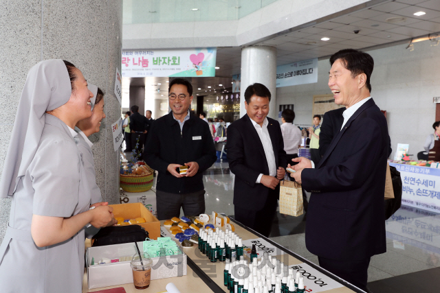 김상균(사진 오른쪽 첫번째) 한국철도시설공단 이사장이 공단 본사 1층에서 열린 ‘2018 사랑 나눔 바자회’에서 물품을 구입한 후 환하게 웃고 있다. 사진제공=한국철도시설공단