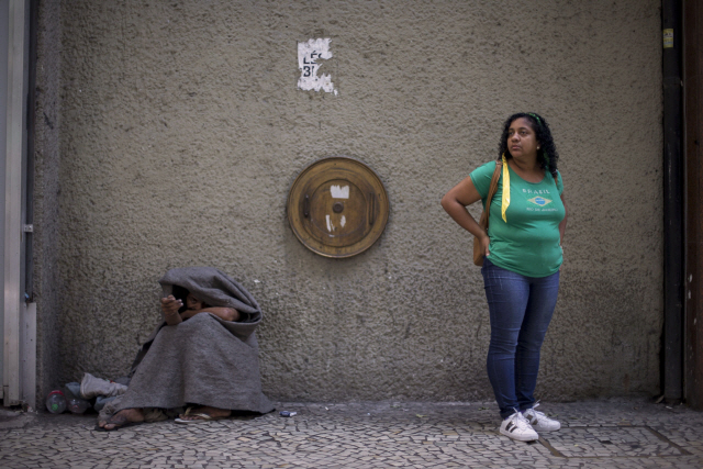 브라질 리우 데 자네이루에서 한 여성이 구걸하는 노숙자 옆에 서 있다./AFP연합뉴스