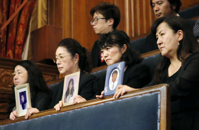 일본 도쿄의 참의원 본회의장에서 29일 과로사로 가족을 잃은 유족들이 상복을 착용한 채 영정을 들고 일하는 방식 개혁 법안에 반대 의사를 밝히고 있다.         /도쿄=교도연합뉴스