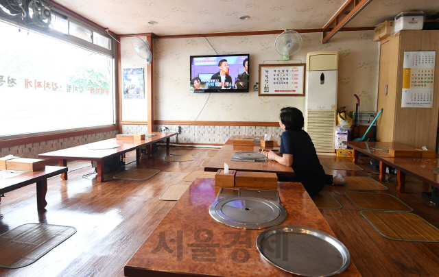 주 52시간 근로시간 단축 시행을 이틀 앞둔 29일 오후 서울의 한 음식점에서 주인이 텅 빈 식당 한가운데 앉아 멍하니 TV를 바라보고 있다.  /권욱기자