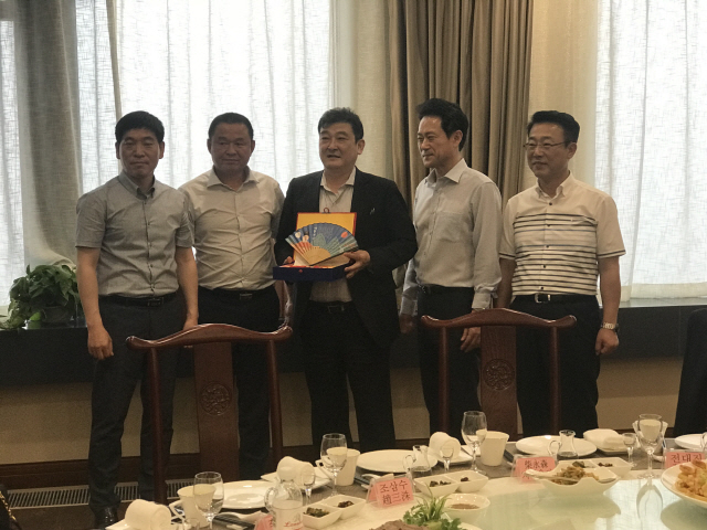 차이융썬(왼쪽 세번째) 더블스타 회장이 지난 5월 중국 칭다오 더블스타 본사를 방문한 금호타이어 노조 관계자들과 함께 선물로 받은 부채를 들어 보이고 있다. /사진제공=금호타이어