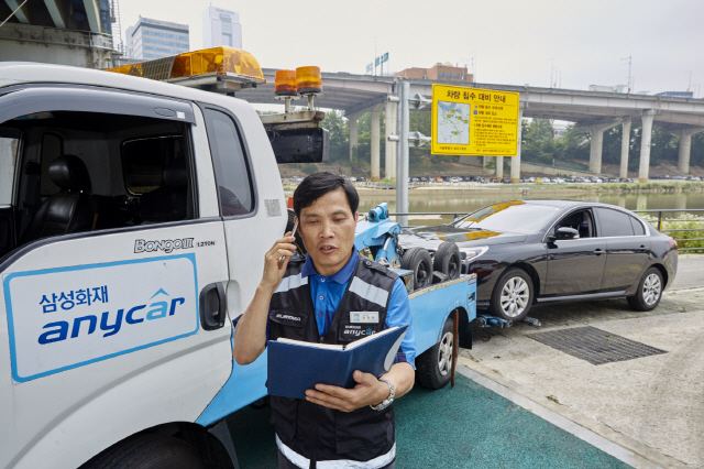 삼성화재 애니카 직원이 침수 위험 지역에 출동해 고객에게 휴대폰으로 차량 침수 위험을 안내하고 있다. /사진제공=삼성화재