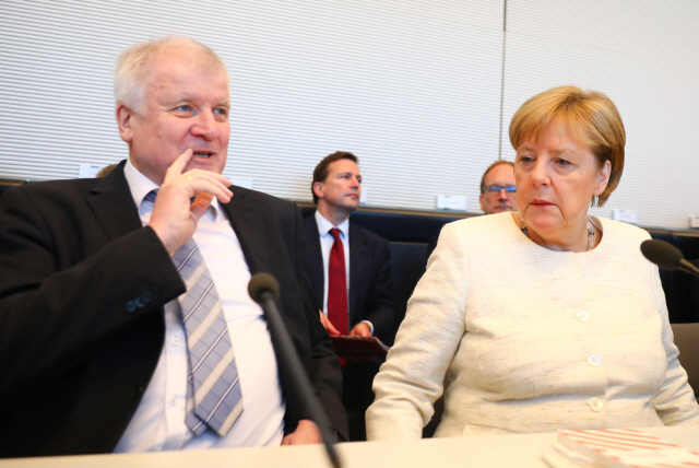 앙겔라 메르켈(오른쪽) 독일 총리와 호르스트 제호퍼 내무장관이 3일(현지시간) 베를린에 위치한 독일 의회에서 만나 이야기를 나누고 있다. /베를린=로이터연합뉴스