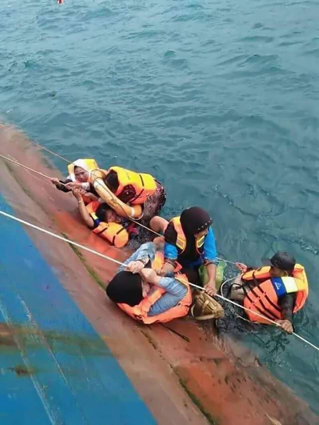 3일(현지시간) 인도네시아 술라웨시섬 근해에서 좌초한 페리선에서 승객들이 구조대원의 도움을 받으며 바다로 탈출하고 있다. /자카르타=AFP연합뉴스