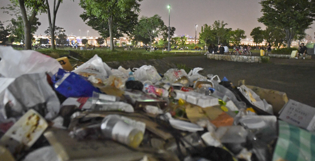 지난달 29일 밤 무더위를 식히려 많은 시민들이 한강 시민공원을 찾은 가운데 한편에 술병 등 쓰레기들이 잔뜩 쌓여 있다./송은석기자