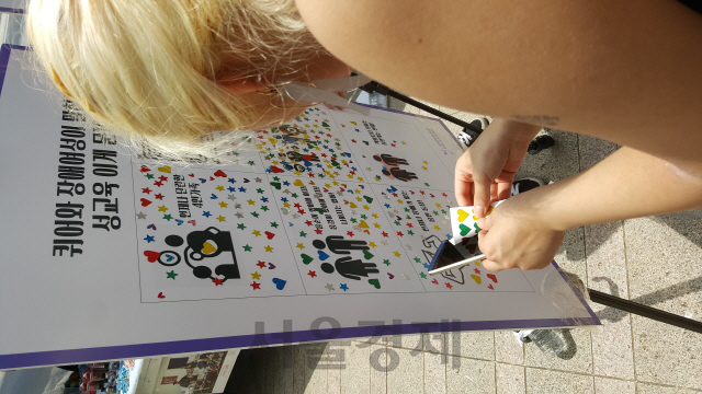 14일 서울 퀴어문화축제에 참여한 한 참가자가 설문조사판에 스티커를 붙이고 있다./서종갑기자
