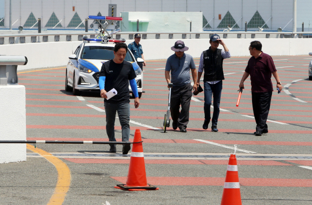 일명 ‘김해공항 BMW 질주사고’가 발생한 부산 강서구 김해공항 국제선 청사 1번 출입구 앞에서 13일 오전 경찰과 국과수가 BMW 차량의 이동 거리를 측정하고, 사고 흔적을 감식하고 있다./연합뉴스