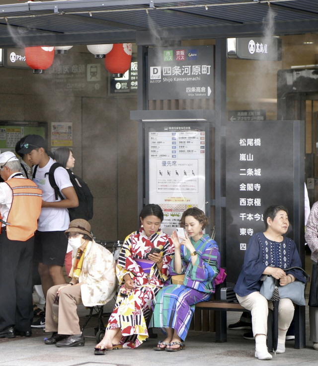 낮 최고기온이 39도를 넘어선 지난 16일 일본 교토 시내의 한 버스정류장에서 시민들이 더위를 피하며 버스를 기다리고 있는 모습./연합뉴스