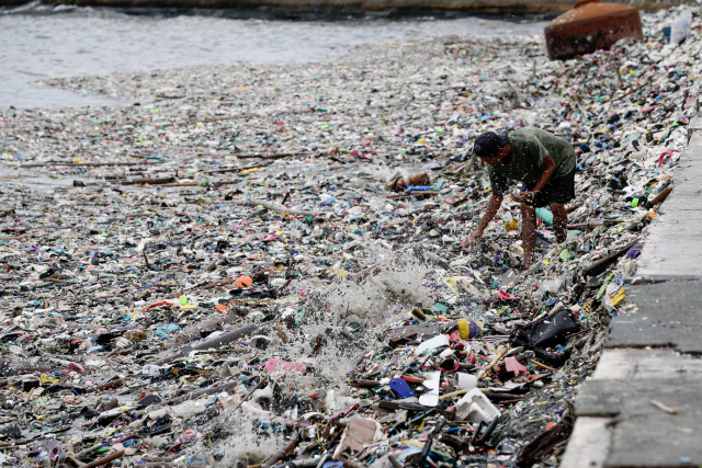 18일(현지시간) 강력한 태풍이 덮쳐 쓰레기로 뒤덮힌 필리핀 마닐라의 해변에서 한 남성이 재활용할만한 물품을 줍고 있다. /마닐라=EPA연합뉴스