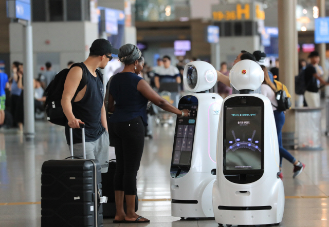 인천국제공항 1터미널 출국장에서 외국인들이 2세대 안내로봇 ‘에어스타(AIRSTAR)’를 살펴보고 있다. /연합뉴스