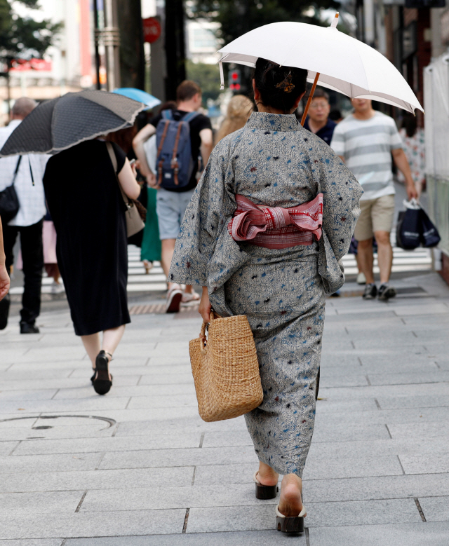 일본에서 불볕더위가 이어지는 가운데 지난 17일(현지시간) 여름 기모노인 ‘유카타’를 차려 입은 여성이 양산을 쓴 채 도쿄 시내를 걸어가고 있다. 18일 일본 기후현 다지미시에선 낮 최고기온이 섭씨 40.6도까지 올랐다. 일본에서 낮 최고기온이 40도를 넘어선 것은 5년만에 처음이다./출처=연합뉴스