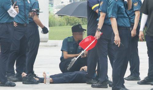 전국 대부분 지역에 폭염 경보가 발령된 24일 오후 서울 광화문 광장에서 근무 중 이던 의무경찰이 쓰러져 구급차를 기다리고 있다./연합뉴스