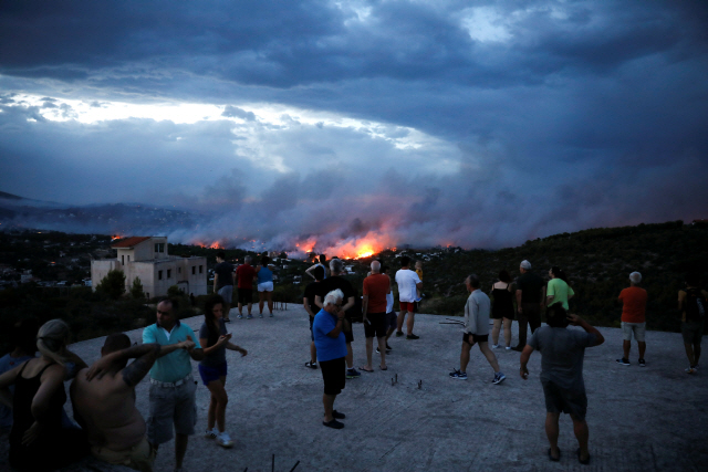 그리스 아테네 근교 라피나 마을 주민들이 23일(현지시간) 가옥까지 집어삼키는 산불을 우려 섞인 표정으로 바라보고 있다.    /라피나=로이터연합뉴스
