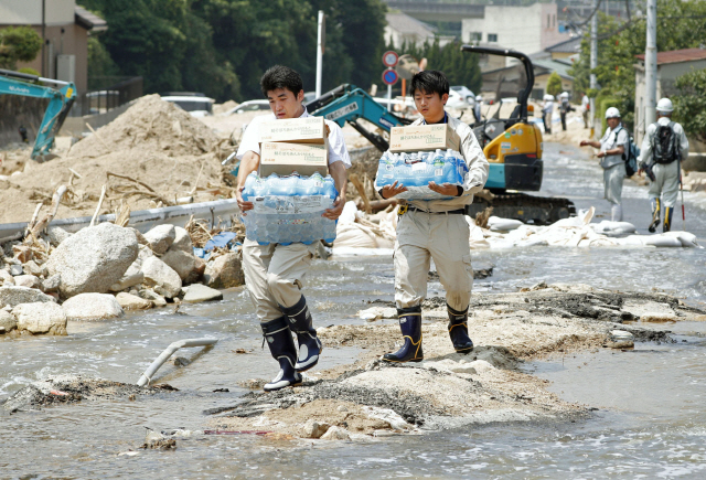 최근 일본 히로시마현 구레시가 폭우로 인해 교통이 마비되자 자원봉사자들이 걸어서 지원물자를 나르고 있다. /연합뉴스