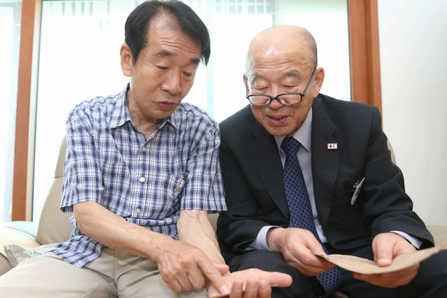 박경서(오른쪽) 대한적십자사 회장이 지난 27일 이산가족 이수남 씨의 서울 용산구 자택을 방문, 북한에 거주하는 큰형 이종성(86) 씨가 살아있다는 북측의 회보서를 직접 전달하고 있다. /사진제공=대한적집자사