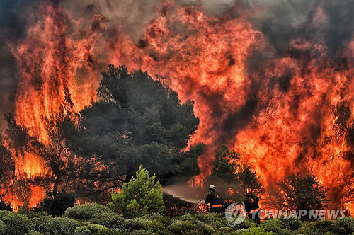 그리스 수도 아테네 인근 키네타에서 시뻘겋게 번져오는 산불을 소방관들이 진화에 나서고 있다./연합뉴스