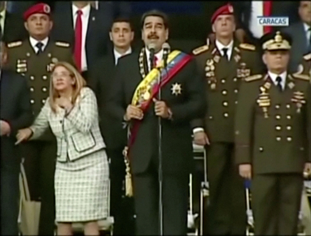 니콜라스 마두로 베네수엘라 대통령(가운데)이 4일(현지시간)수도 카라카스에서 열린 군 행사에서 야외 연설을 하는 도중 발생한 굉음에 놀란 듯 위를 쳐다보고 있다./카라카스=로이터연합뉴스