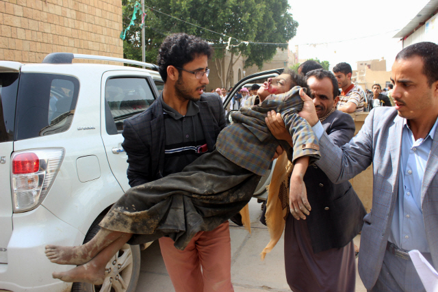 9일(현지시간) 성인 남성들이 예멘 북부 사다주 자흐얀 지역에서 사우디아라비아군에게 폭격을 당한 어린이를 옮기고 있다. /자흐얀=AFP연합뉴스